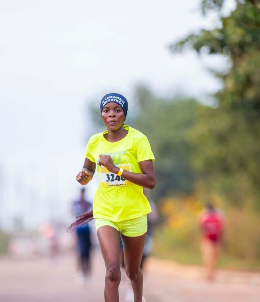 A woman running a half marathon in a bright yellow race top
